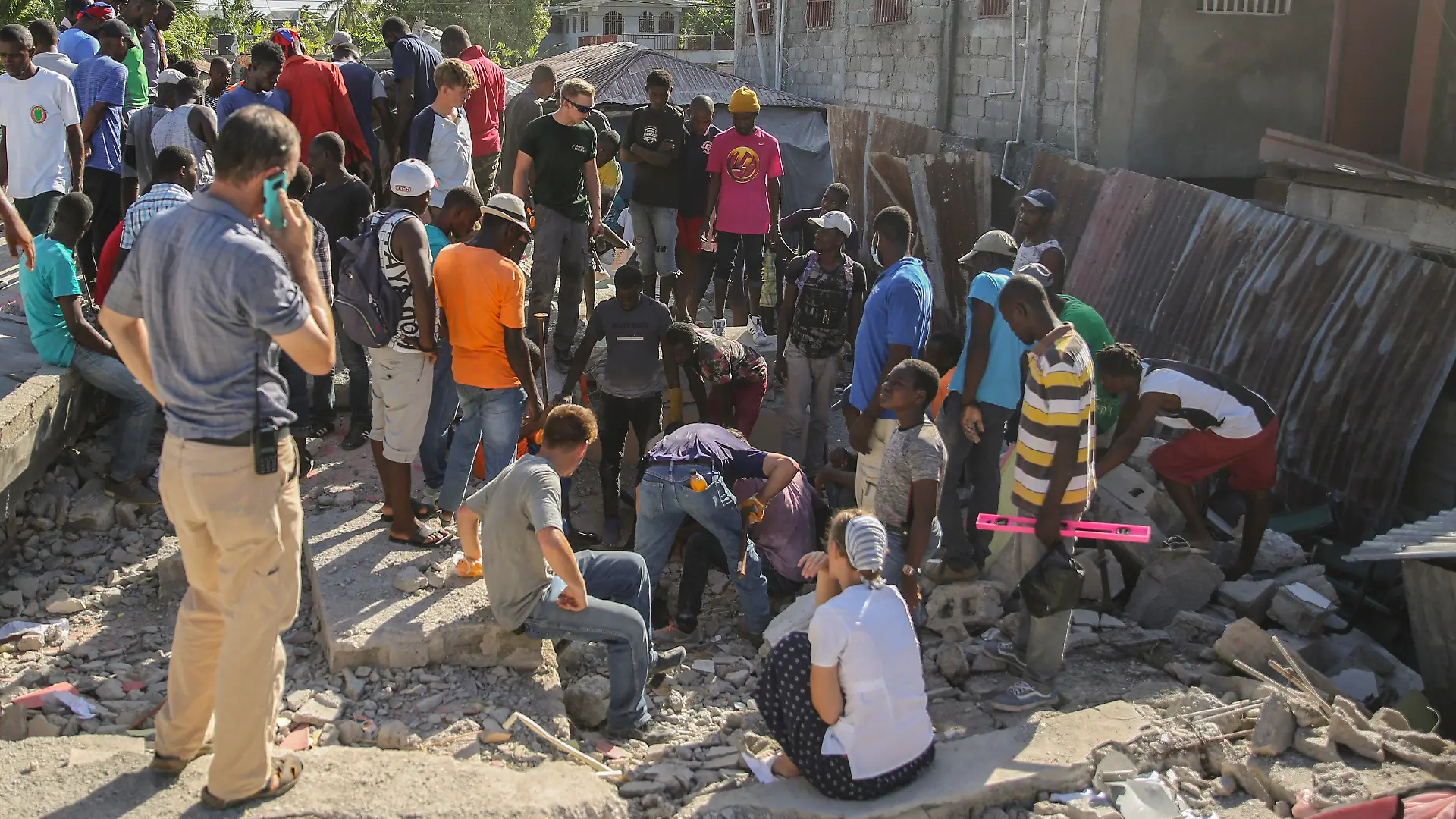 14.08.2021, Haiti, Les Cayes: Menschen suchen nach Überlebenden in einem vom Erdbeben zerstörten Haus in Les Cayes, Haiti. Ein Erdbeben der Stärke 7,2 hat Haiti am Samstag erschüttert. Das Epizentrum lag etwa 125 Kilometer westlich der Hauptstadt Port-au-Prince, teilte der US Geological Survey mit. Foto: Joseph Odelyn/AP/dpa +++ dpa-Bildfunk +++