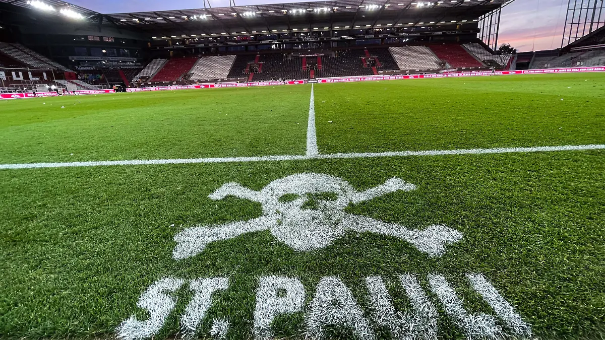 13.08.2021, Hamburg: Fußball: 2. Bundesliga, FC St. Pauli - Hamburger SV, 3. Spieltag im Millerntor-Stadion. Das Logo von St.Pauli ist an der Mittellinie vor den Trainerbänken auf den Rasen gesprüht. Foto: Christian Charisius/dpa - WICHTIGER HINWEIS: Gemäß den Vorgaben der DFL Deutsche Fußball Liga bzw. des DFB Deutscher Fußball-Bund ist es untersagt, in dem Stadion und/oder vom Spiel angefertigte Fotoaufnahmen in Form von Sequenzbildern und/oder videoähnlichen Fotostrecken zu verwerten bzw. verwerten zu lassen. +++ dpa-Bildfunk +++