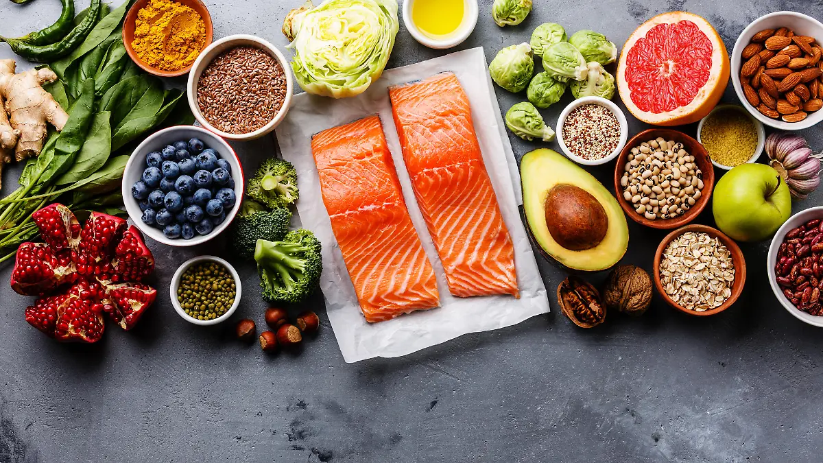 Healthy food clean eating selection: fish, fruit, vegetable, seeds, superfood, cereals, leaf vegetable on gray concrete background copy space