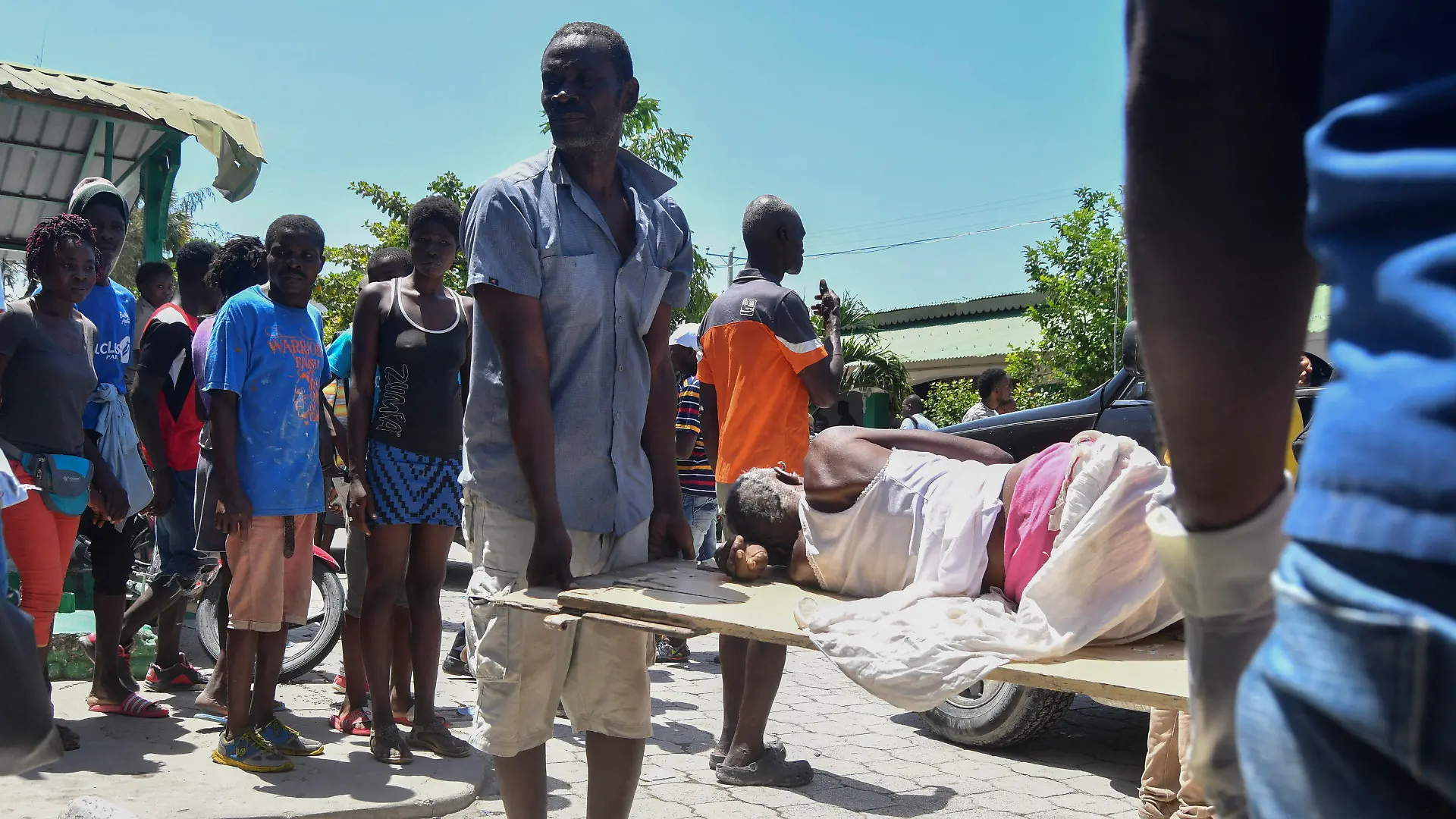 14.08.2021, Haiti, Les Cayes: Ein Mann hilft beim Tragen einer Person, die nach einem Erdbeben aus den Trümmern gerettet wurde. Ein schweres Erdbeben der Stärke 7,2 hat den Süden des Karibikstaates Haiti erschüttert. Dabei kamen mehrere Menschen ums Leben. Foto: Duples Plymouth/AP/dpa +++ dpa-Bildfunk +++