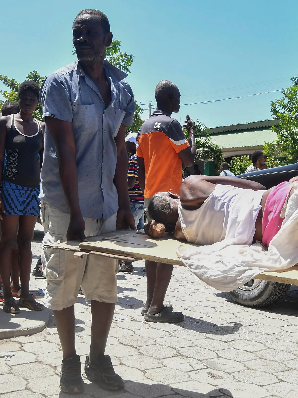 14.08.2021, Haiti, Les Cayes: Ein Mann hilft beim Tragen einer Person, die nach einem Erdbeben aus den Trümmern gerettet wurde. Ein schweres Erdbeben der Stärke 7,2 hat den Süden des Karibikstaates Haiti erschüttert. Dabei kamen mehrere Menschen ums Leben. Foto: Duples Plymouth/AP/dpa +++ dpa-Bildfunk +++