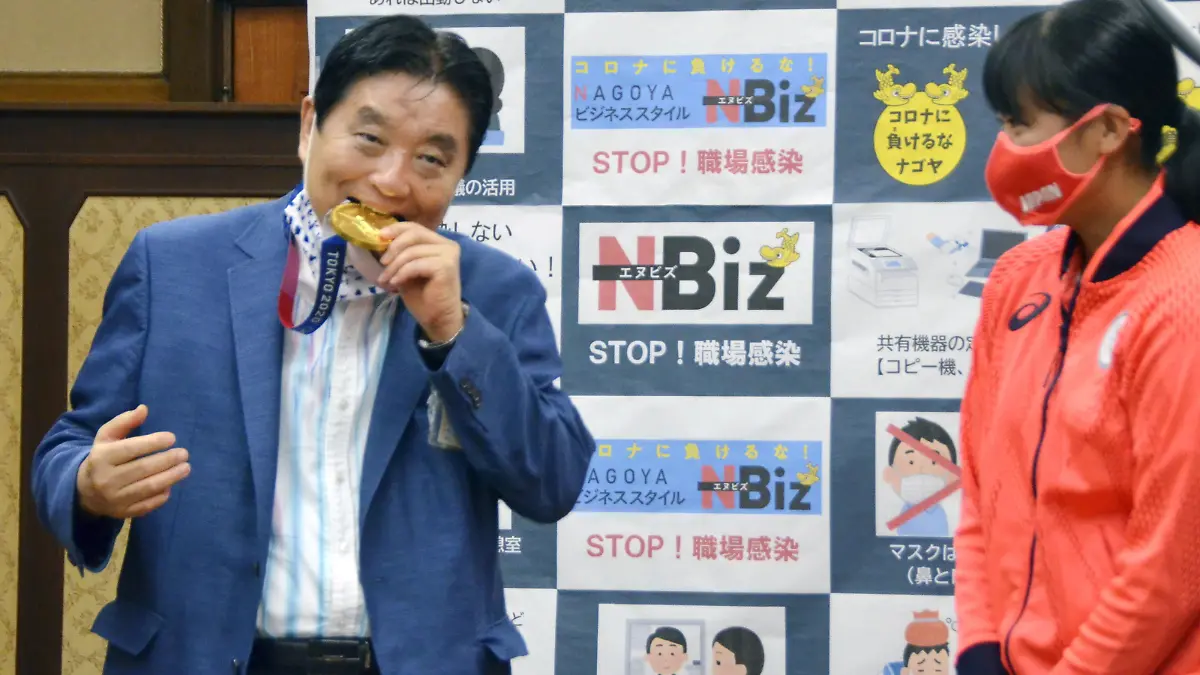 Nagoya city Mayor Takashi Kawamura bites the Tokyo 2020 Olympic Games gold medal of the softball athlete Miu Goto during a ceremony in Nagoya, central Japan, August 4, 2021, in this photo taken by Kyodo. Picture taken August 4, 2021. Mandatory credit Kyodo/via REUTERS ATTENTION EDITORS - THIS IMAGE WAS PROVIDED BY A THIRD PARTY. MANDATORY CREDIT. JAPAN OUT. NO COMMERCIAL OR EDITORIAL SALES IN JAPAN.