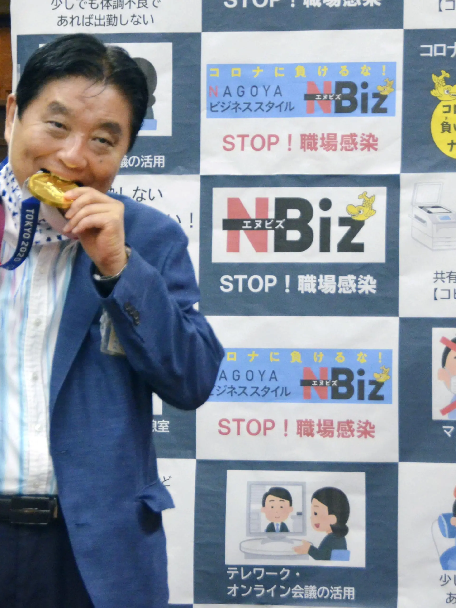 Nagoya city Mayor Takashi Kawamura bites the Tokyo 2020 Olympic Games gold medal of the softball athlete Miu Goto during a ceremony in Nagoya, central Japan, August 4, 2021, in this photo taken by Kyodo. Picture taken August 4, 2021. Mandatory credit Kyodo/via REUTERS   ATTENTION EDITORS - THIS IMAGE WAS PROVIDED BY A THIRD PARTY. MANDATORY CREDIT. JAPAN OUT. NO COMMERCIAL OR EDITORIAL SALES IN JAPAN.