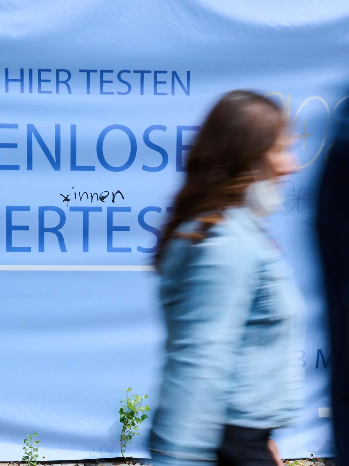 PRODUKTION - 09.08.2021, Berlin: «Kostenlose Bürgertests» steht auf einem Plakat während Personen vorüber gehen. Die Regierungschefs der Länder beraten am 10.08.2021 mit Bundeskanzlerin Merkel über den weiteren Umgang mit Corona-Impfungen und Tests. Foto: Annette Riedl/dpa +++ dpa-Bildfunk +++