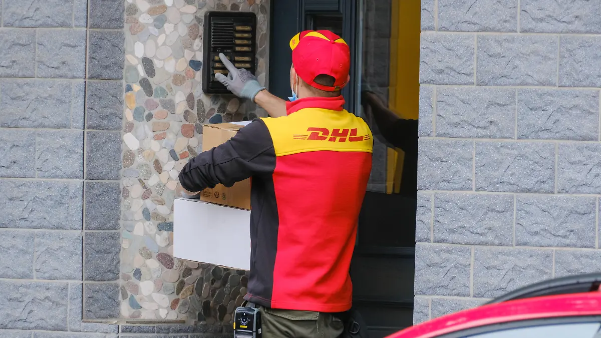 Paketbote von DHL klingelt an einer Haustür