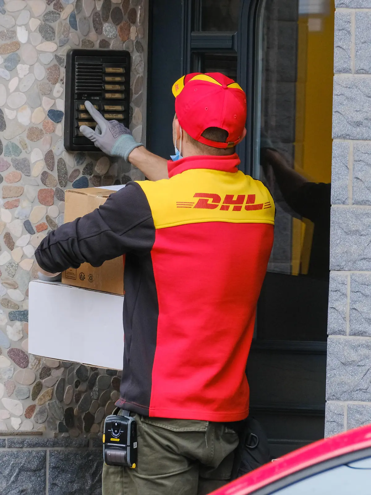 Paketbote von DHL klingelt an einer Haustür