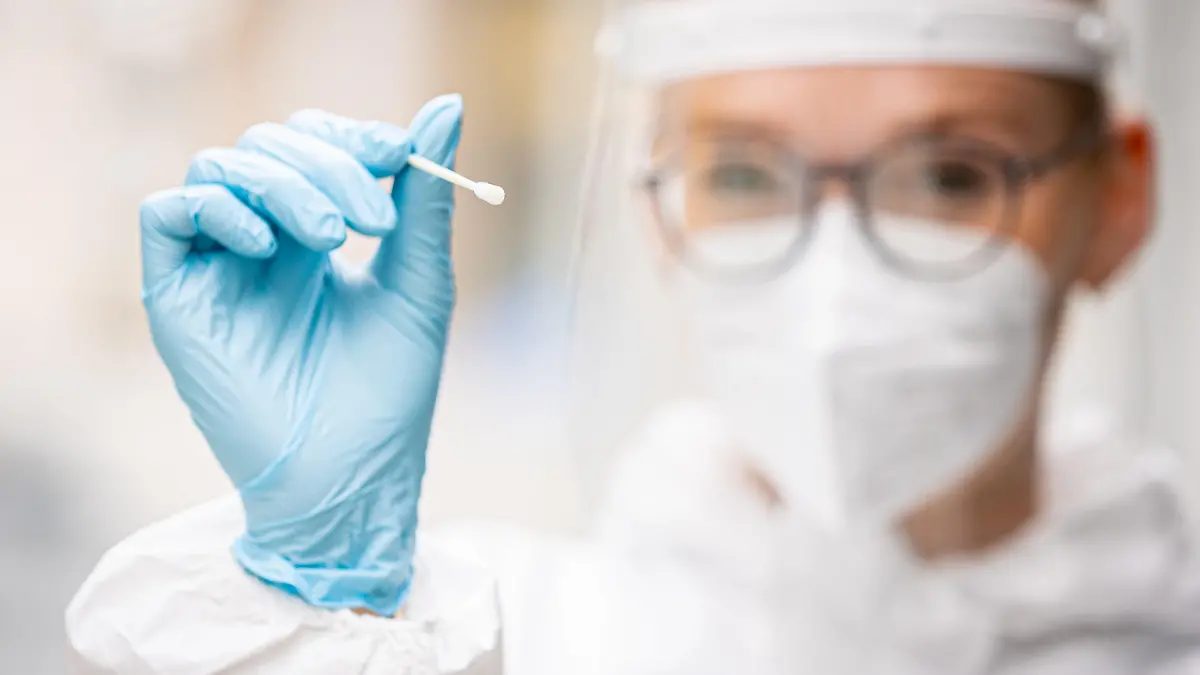 ARCHIV - 27.07.2021, Niedersachsen, Hannover: Eine Mitarbeiterin des Testzentrums am Platz der Weltausstellung hält einen Teststab für einen Schnelltest auf das Coronavirus in ihren Händen (gestellte Szene). Im Zuge der immer stärkeren Ausbreitung der Delta-Variante des Coronavirus hat sich die Sieben-Tage-Inzidenz in Deutschland innerhalb eines Monats etwa vervierfacht. (zu dpa «Delta lässt Corona-Inzidenz steigen - bislang wenig schwere Verläufe») Foto: Moritz Frankenberg/dpa +++ dpa-Bildfunk +++