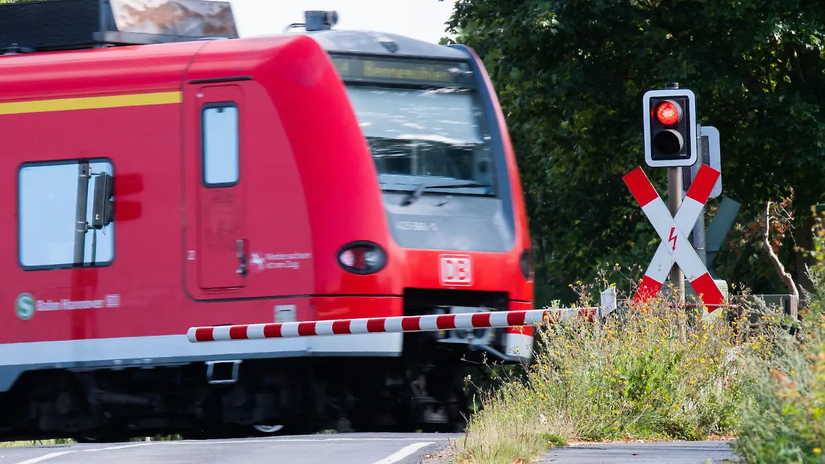 10.08.2021, Niedersachsen, Rössing: Eine S-Bahn der Deutschen Bahn (DB) fährt an einem Bahnübergang mit einer roten Ampel vorbei. Die Gewerkschaft Deutscher Lokomotivführer (GDL) gibt an diesem Dienstag das Ergebnis der Urabstimmung zum Arbeitskampf bei der Deutschen Bahn bekannt. Foto: Julian Stratenschulte/dpa +++ dpa-Bildfunk +++