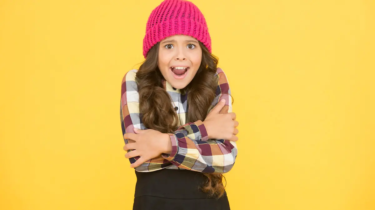 She is cold. Unhappy little child feel cold yellow background. Small girl shiver in cold weather headwear. Crispy autumn or winter season. Chilly and cold. Coldness.