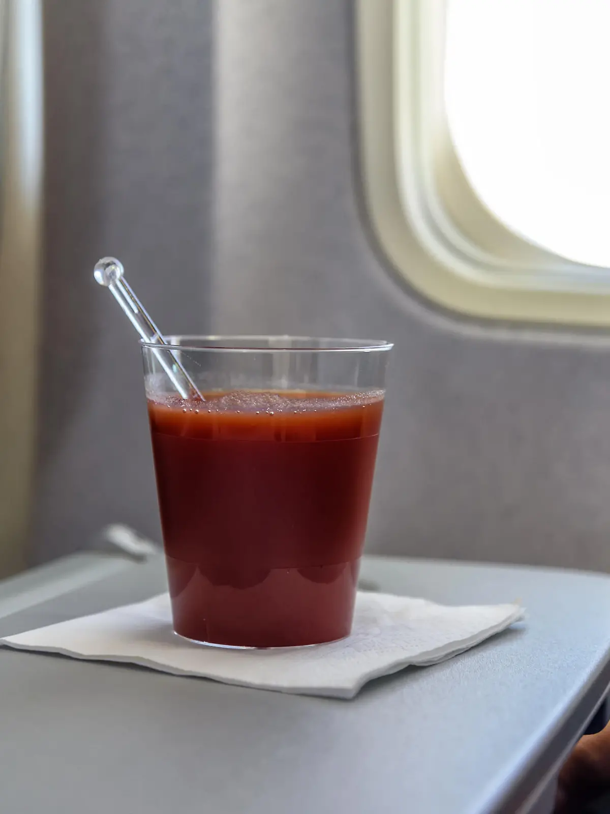 Ein Becher Tomatensaft auf einem Tisch im Flugzeug