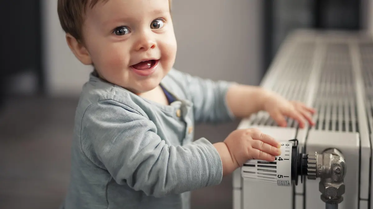 Portrait of smiling baby boy playing with thermostat of heater model released Symbolfoto property released PUBLICATIONxINxGERxSUIxAUTxHUNxONLY SEBF00022