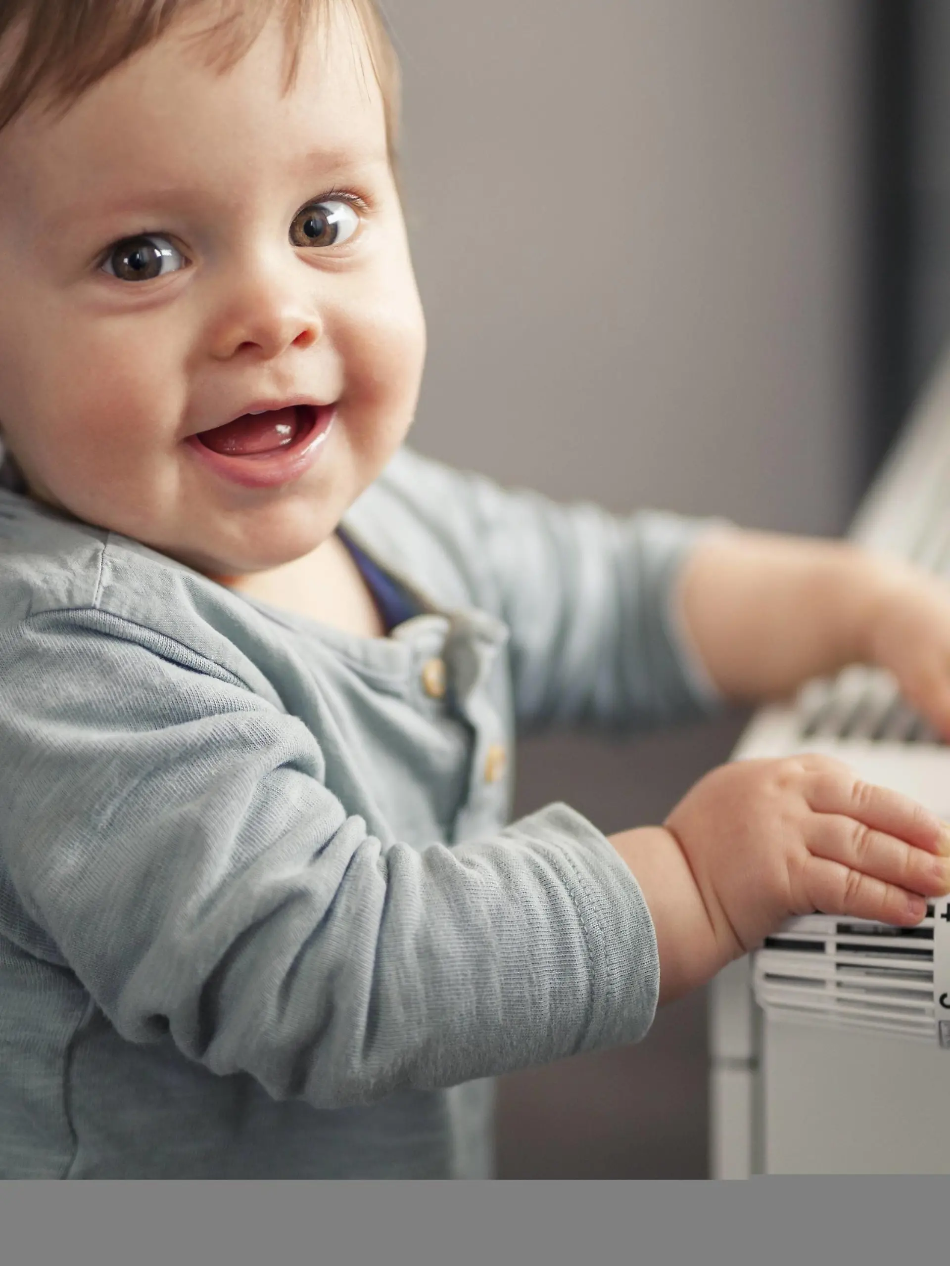  Portrait of smiling baby boy playing with thermostat of heater model released Symbolfoto property released PUBLICATIONxINxGERxSUIxAUTxHUNxONLY SEBF00022