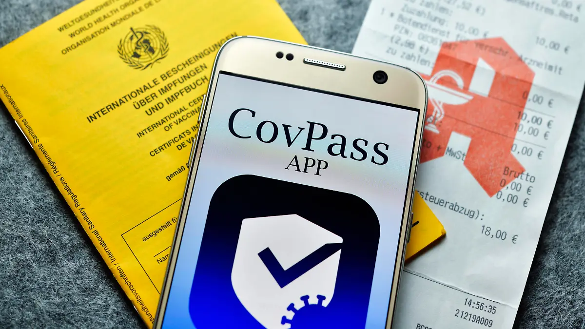 Smartphone mit Impfpass-App, Impfausweis und Apotheken-Kassenzettel, Symbolfoto digitaler Impfnachweis *** Smartphone with vaccination card app, vaccination card and pharmacy receipt, symbol photo digital proof of vaccination 