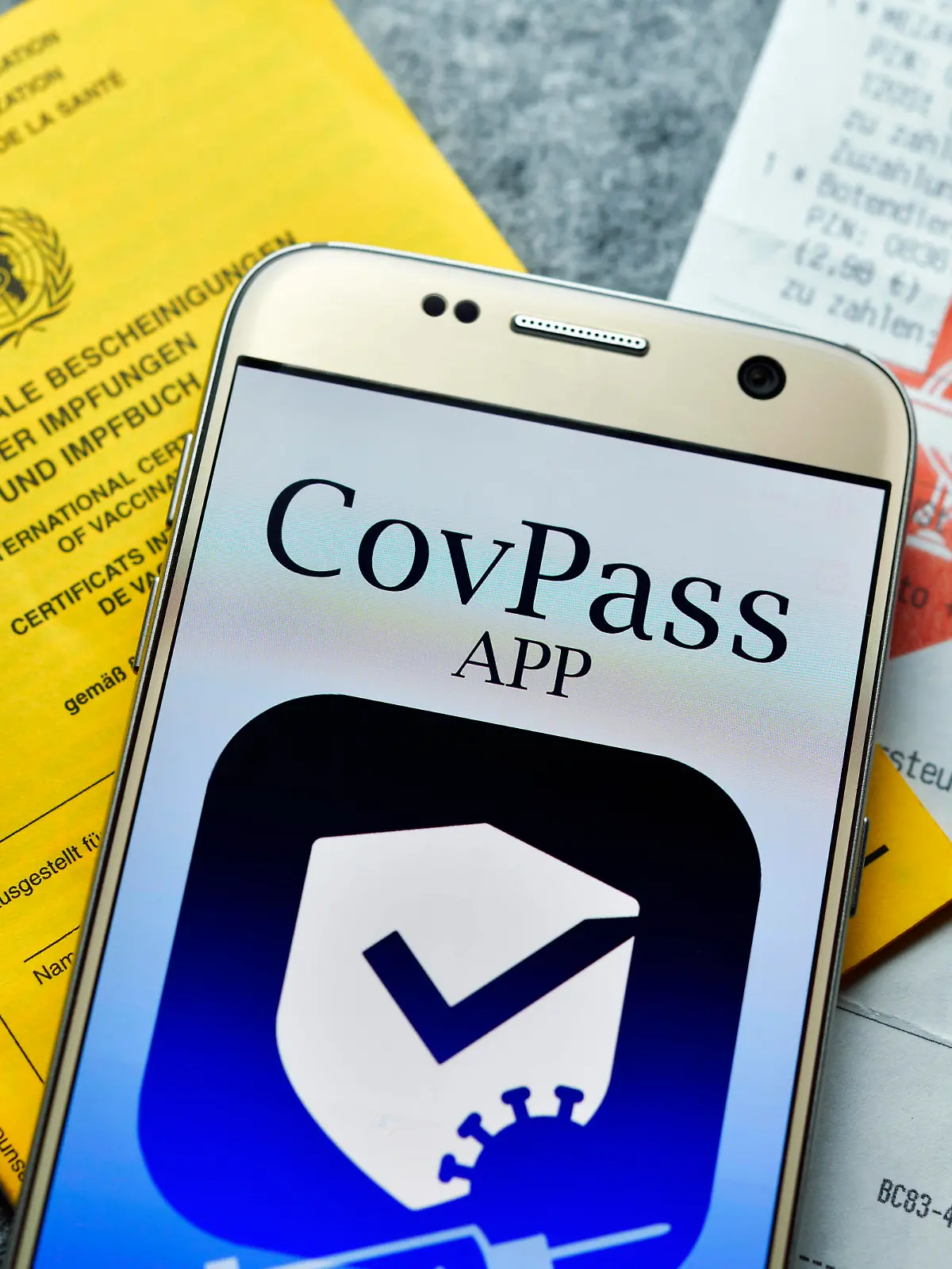 Smartphone mit Impfpass-App, Impfausweis und Apotheken-Kassenzettel, Symbolfoto digitaler Impfnachweis *** Smartphone with vaccination card app, vaccination card and pharmacy receipt, symbol photo digital proof of vaccination 