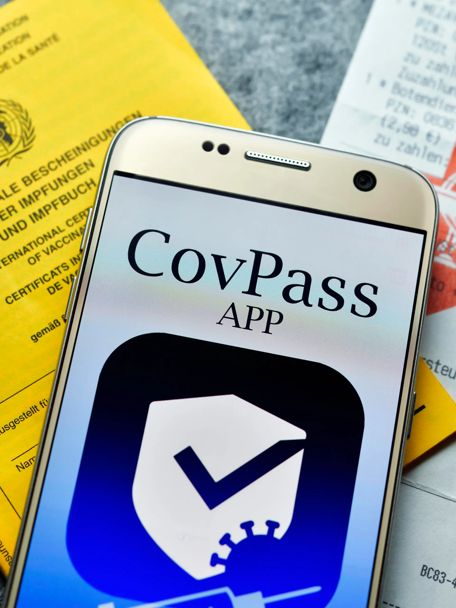 Smartphone mit Impfpass-App, Impfausweis und Apotheken-Kassenzettel, Symbolfoto digitaler Impfnachweis *** Smartphone with vaccination card app, vaccination card and pharmacy receipt, symbol photo digital proof of vaccination 