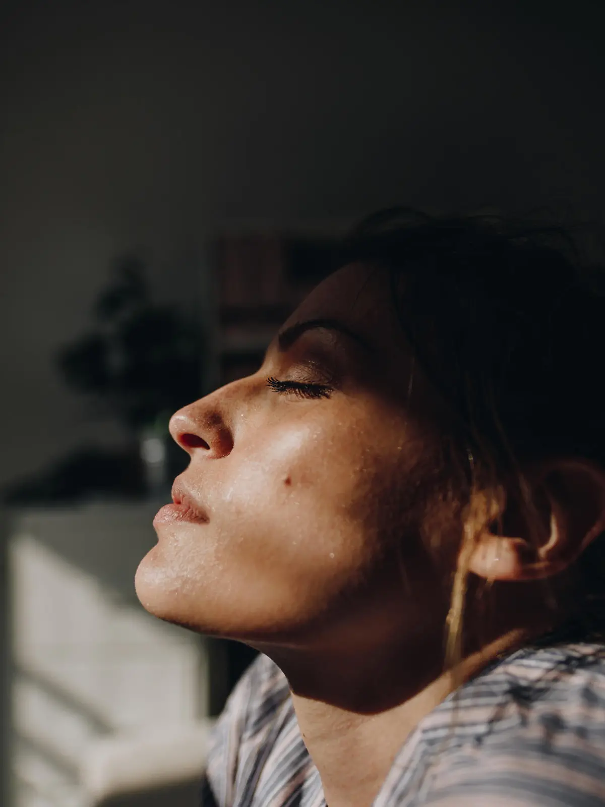 Eine Frau mit geschlossenen Augen. Das Gesicht der Frau wird von der Sonne angestrahlt.