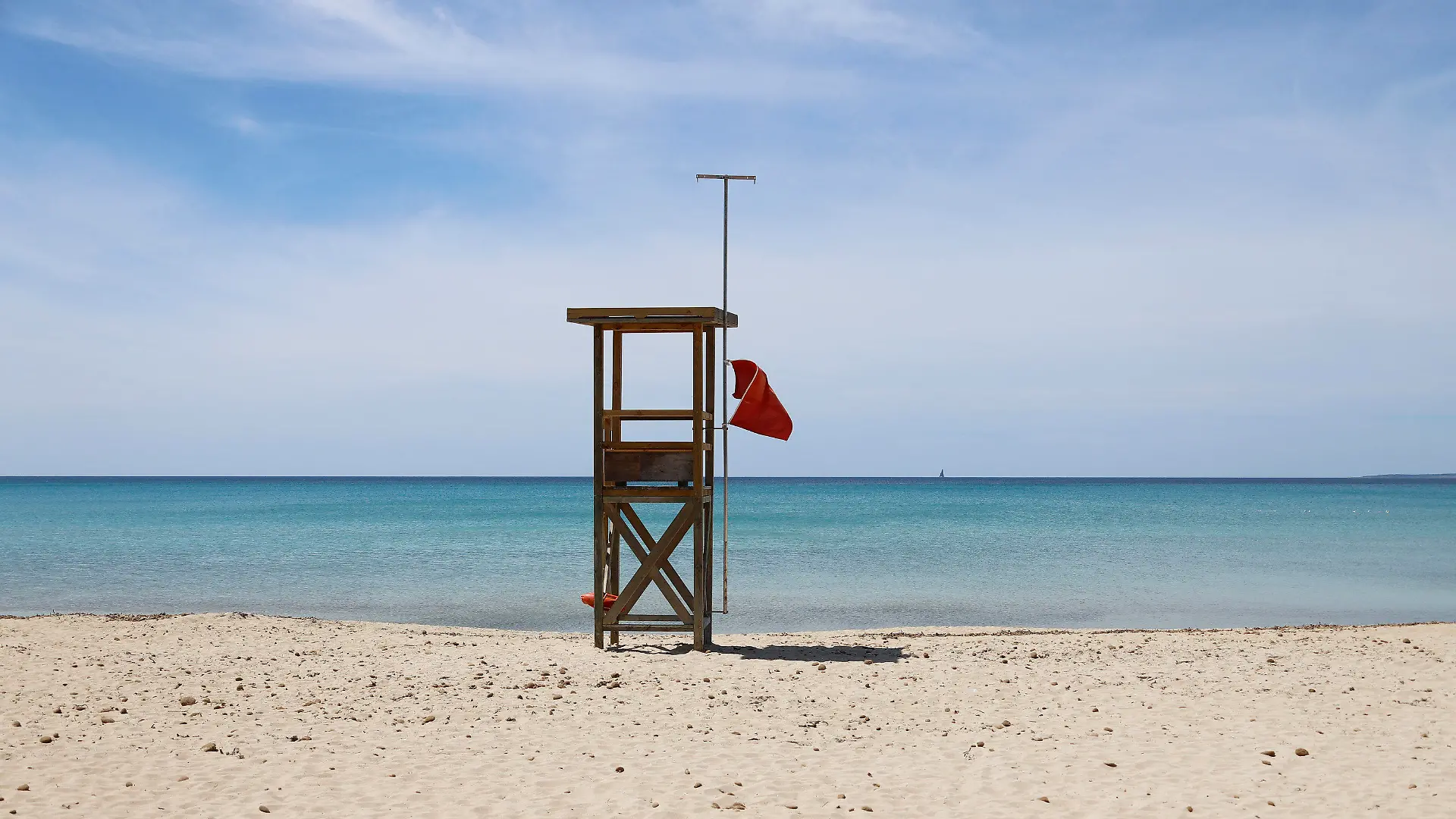 07.05.2020, Spanien, Palma: Eine rote Flagge weht am Strand von Arenal, um das Schwimmen zu verbieten. Die Abwesenheit von Touristen ist an den Stränden Mallorcas spürbar. «Das Wasser ist derzeit spektakulär transparent», sagt der Biologe Txema Brotons. (zu dpa "Mallorca ohne Urlauber - ein Segen für die Umwelt?") Foto: Clara Margais/dpa +++ dpa-Bildfunk +++