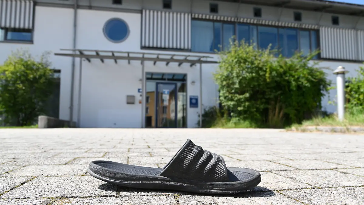 10.08.2021, Bayern, Miesbach: Eine Gummisandale liegt vor der Polizeiinspektion. Mitglieder einer Großfamilie wollten sich Zugang zur Polizeistation verschaffen und griffen die Beamten mit Steinen an. Vorausgegangen war die Festnahme einer Person wegen Verdachts auf ein Sexualdelikt. Foto: Tobias Hase/dpa +++ dpa-Bildfunk +++