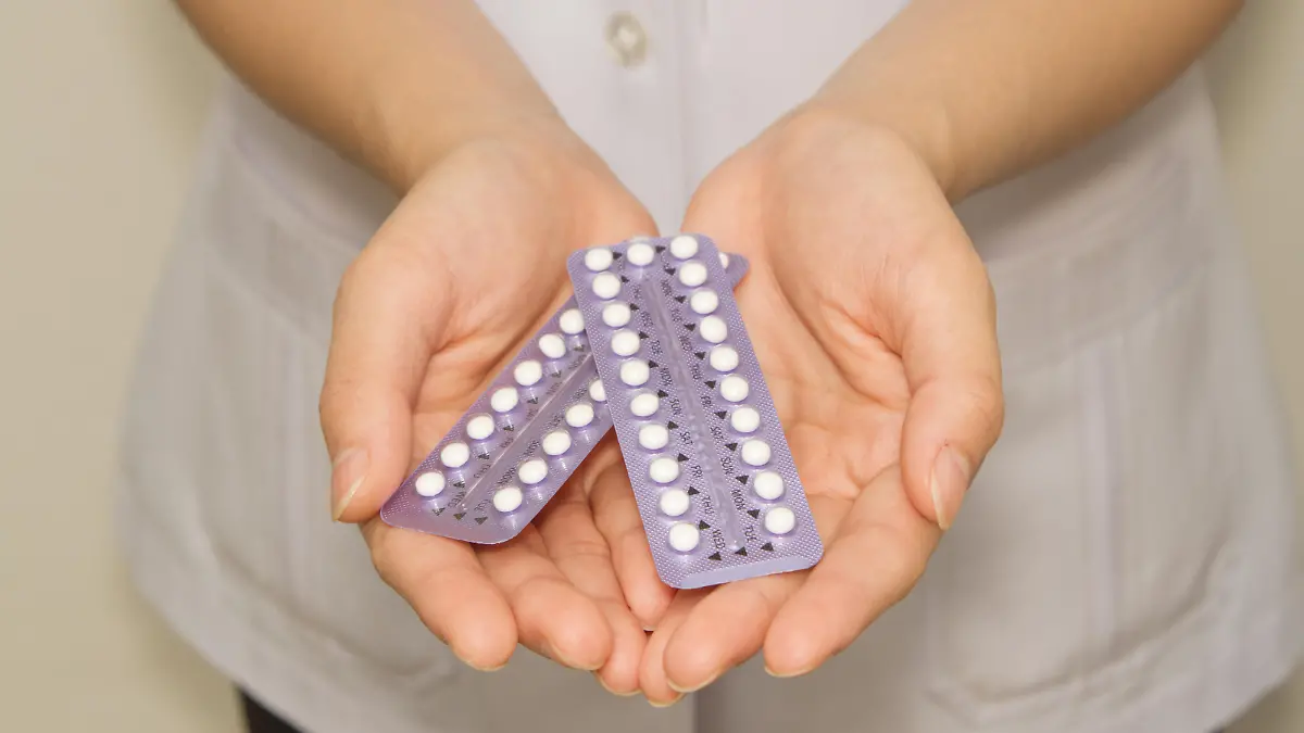 doctor's hand holding the birth control pills