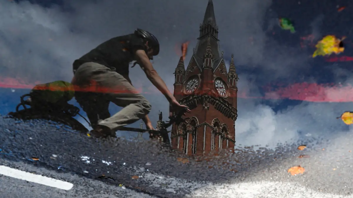 29.07.2021, Großbritannien, London: Ein Radfahrer spiegelt sich in einer Pfütze, als er vor dem Bahnhof St Pancras entlang fährt. Geimpfte Reisende aus den USA und vielen europäischen Ländern können ab der kommenden Woche wieder ohne Quarantänepflicht nach England einreisen. Die britische Regierung teilte heute mit, Menschen, die beide Dosen eines in den USA und der EU zugelassenen Impfstoffs erhalten hätten, könnten sich vor und nach der Ankunft in England auf das Coronavirus testen lassen, statt sich selbst zu isolieren. Foto: Han Yan/Xinhua/dpa +++ dpa-Bildfunk +++