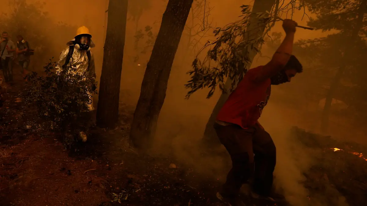 08.08.2021, Griechenland, Pefki: Personen versuchen einen Waldbrand in einem rauchverhangenen Waldstück in der Nähe des Dorfes Pefki auf der Insel Euböa zu löschen. Erstmals seit Beginn der Waldbrände auf der Insel Euböa Anfang der Woche sind dort massive Lufteinsätze gegen die Flammen geflogen worden. Foto: Petros Karadjias/AP/dpa +++ dpa-Bildfunk +++