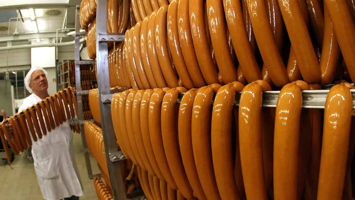 ARCHIV - Geräucherte und gegarte Currywürste werden am 03.01.2008 in der werkseigenen VW-Fleischerei in Wolfsburg (Niedersachsen) von Räucherkörben genommen. Die Volkswagen-eigene Currywurst-Produktion hat auch 2014 den globalen Autoabsatz des Pkw-Herstellers wieder locker überholt. Foto: Holger Hollemann dpa (zu dpa «Currywurst-Wachstum bei VW stellt Autoabsatz abermals in den Schatten» vom 17.01.2015) +++(c) dpa - Bildfunk+++