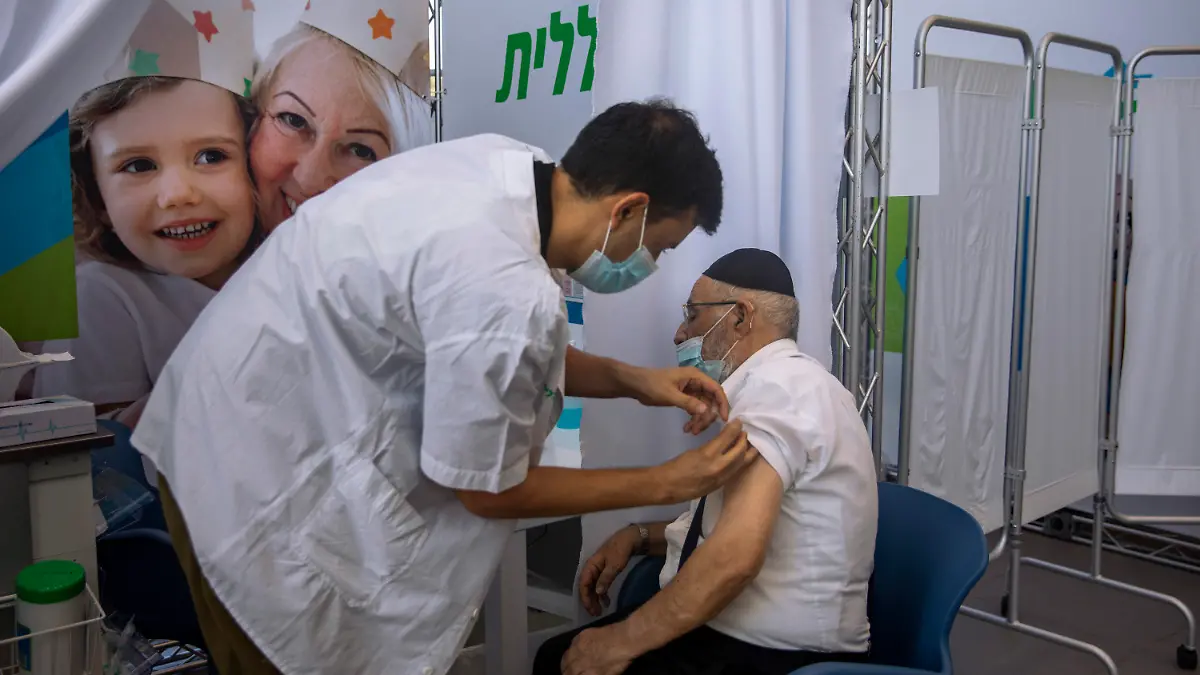 10.08.2021, Israel, Tel Aviv: Ein Mann erhält eine dritte Dosis des Corona-Impfstoffes von Biontech/Pfizer von einem medizinischen Mitarbeiter in einem Impfzentrum. Israel hat mit einer Welle von Corona-Infektionen zu kämpfen und empfiehlt Menschen über 60 Jahre, eine Auffrischungsimpfung wahrzunehmen. Israel als erstes Land damit begonnen, Menschen über 60 Jahren eine dritte Impfdosis gegen das Coronavirus zu geben. Foto: Oded Balilty/AP/dpa +++ dpa-Bildfunk +++