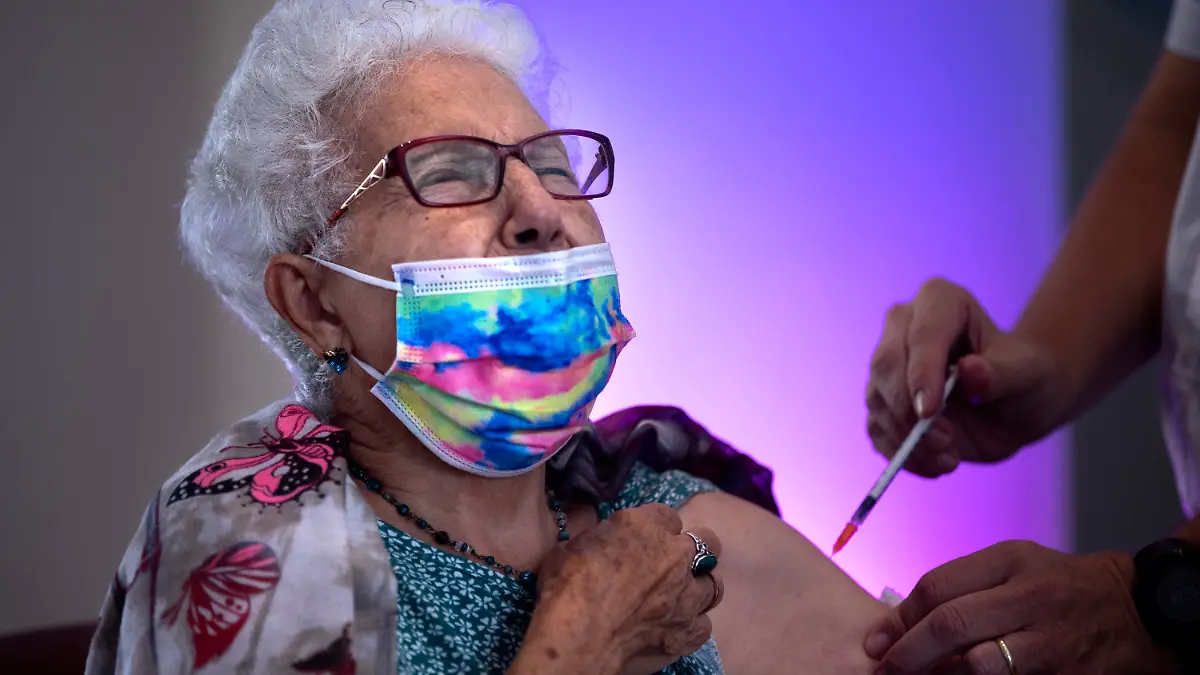 ARCHIV - 01.08.2021, Israel, Netanya: Der 83-jährige Rachel Gershon (l) wird in einem privaten Pflegeheim eine dritte Dosis des Corona-Impfstoffs von Biontech/Pfizer injiziert. Nach einer dritten Corona-Impfung hat eine Mehrheit von Befragten in Israel über ähnliche Impfreaktionen wie nach der zweiten Spritze berichtet. (zu dpa «Israelische Studie: Nach dritter Corona-Impfung ähnliche Reaktion») Foto: Oded Balilty/AP/dpa +++ dpa-Bildfunk +++
