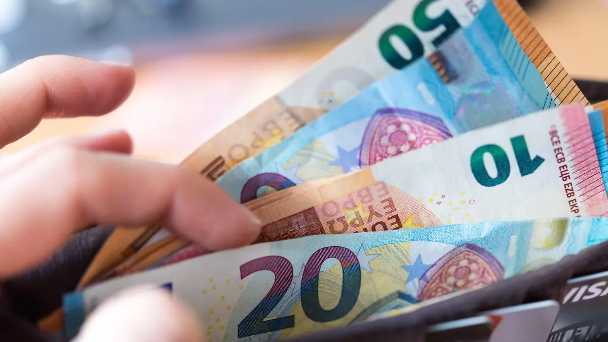 ARCHIV - 04.12.2018, Sachsen, Dresden: ILLUSTRATION - Eine Frau hält eine Geldbörse mit Banknoten in der Hand. Trotz riesiger Hilfsprogramme für die Wirtschaft in der Corona-Krise, erwarten Ökonomen keine Inflation. Foto: Monika Skolimowska/dpa-Zentralbild/dpa +++ dpa-Bildfunk +++