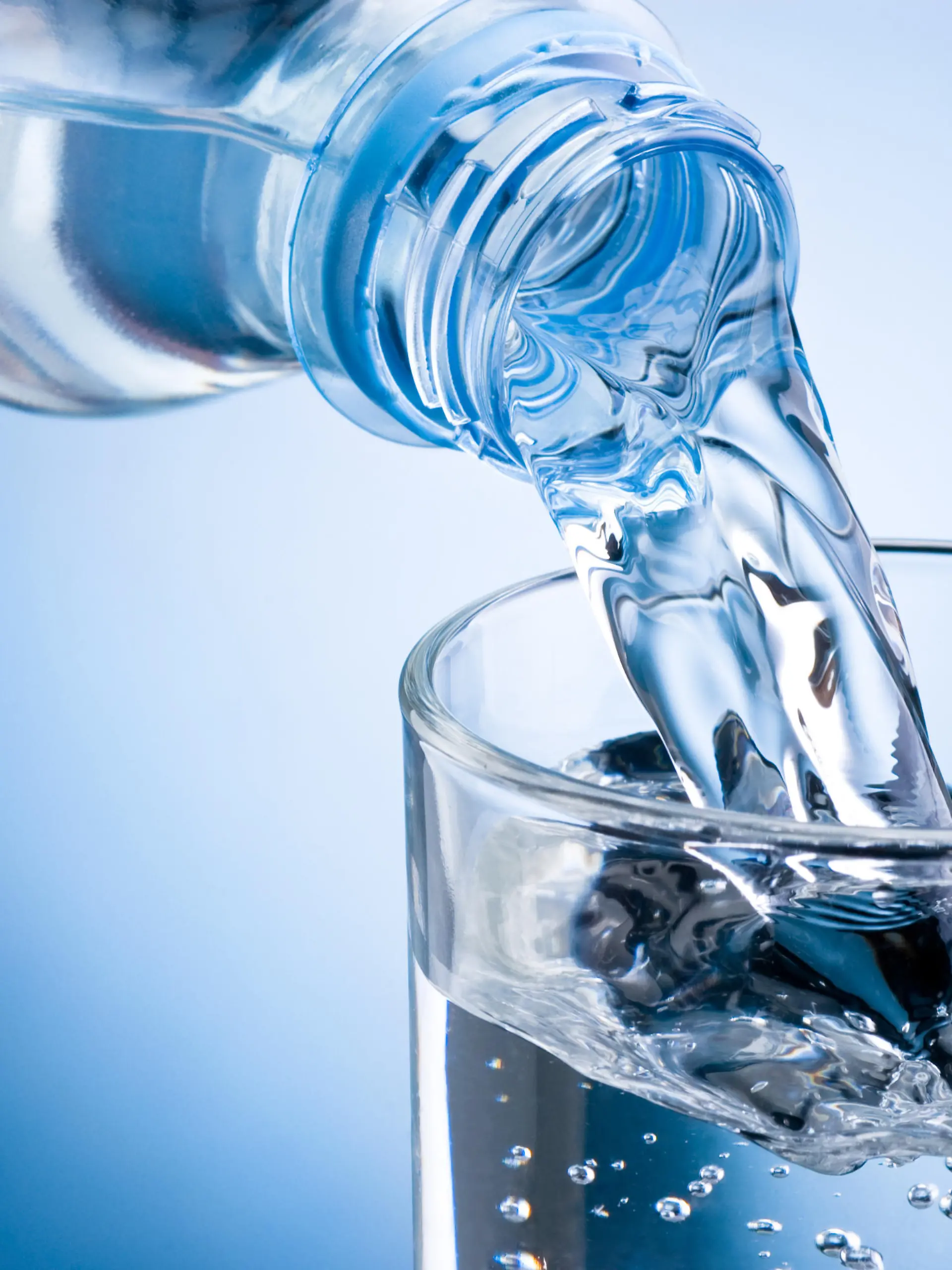 Mineralwasser aus Flasche wird in Glas eingeschenkt