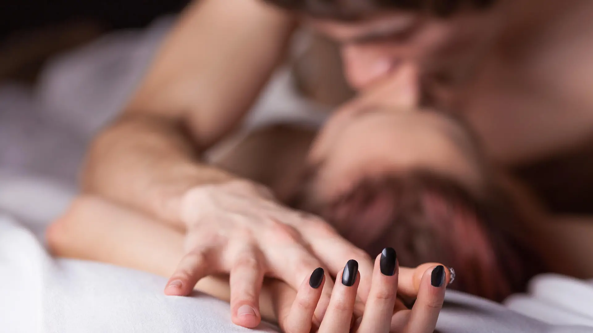 Young beautiful amorous couple making love in bed on white background