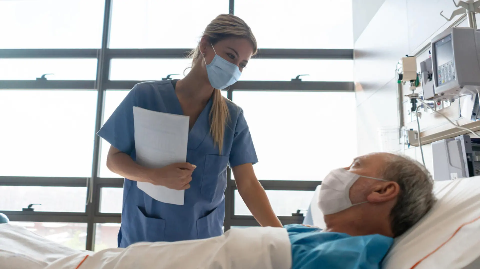 Krankenpflegerin betreut Patient im Krankenhausbett