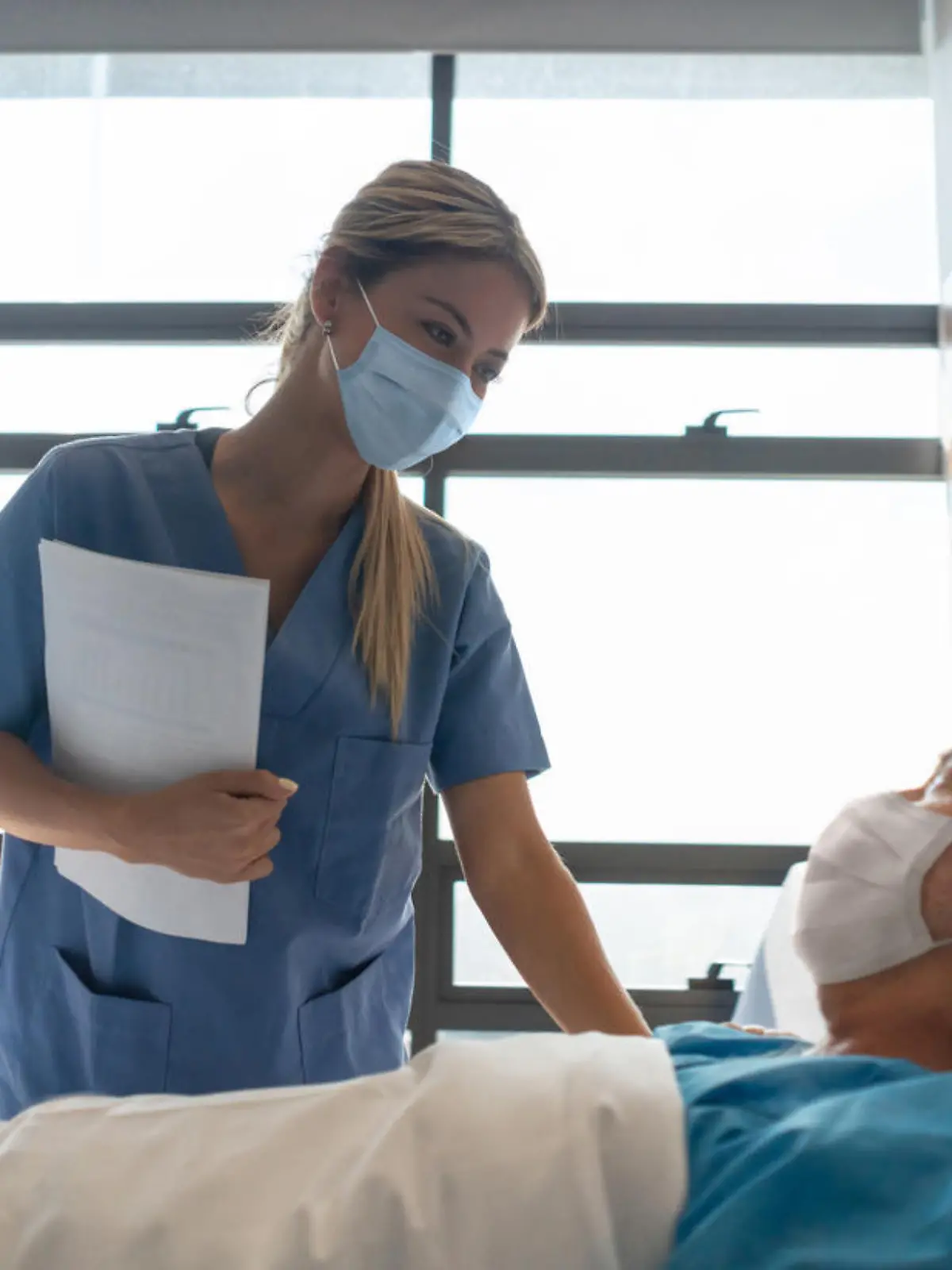 Krankenpflegerin betreut Patient im Krankenhausbett