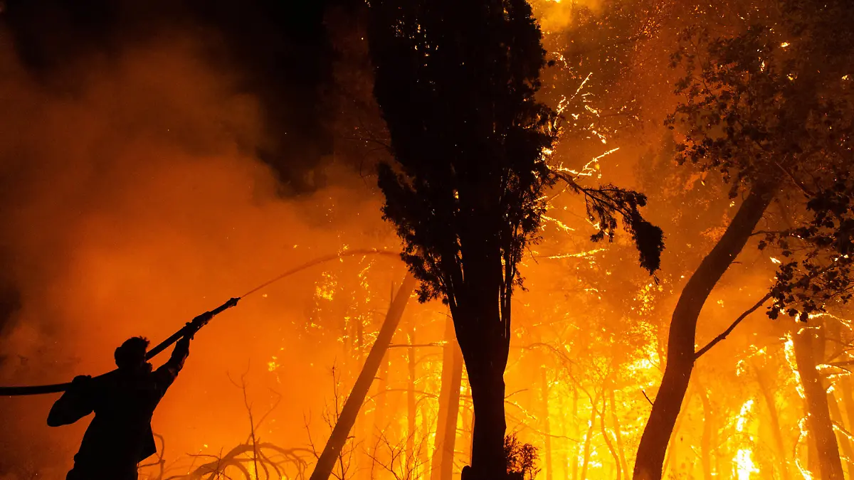 05.08.2021, Griechenland, Athen: Ein Feuerwehrmann hält einen Wasserschlauch während der Löscharbeiten eines Waldbrandes im Norden von Athen. Die Feuerwehr kämpft unermüdlich, um die Brände einzudämmen, die in ganz Griechenland ausgebrochen sind. Die Waldbrände im Norden von Athen sind am Donnerstag wieder aufgeflammt, und auch auf der Insel Euböa, im antiken Olympia auf dem nordwestlichen Peloponnes und in anderen Teilen des Landes sind die Feuer wieder ausgebrochen. Foto: Marios Lolos/XinHua/dpa +++ dpa-Bildfunk +++