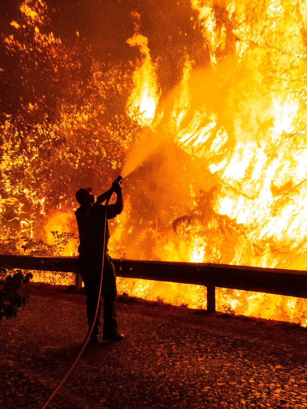 dpatopbilder - 05.08.2021, Griechenland, Athen: Freiwillige Helfer unterstützten einen Feuerwehrmann bei den Löscharbeiten eines Waldbrandes udn schlagen hinter ihm Flammen aus. Im von verheerenden Waldbränden getroffenen Griechenland spitzt sich die Lage weiter zu. Seit den frühen Morgenstunden fachten starke Westwinde am Freitag die zahlreichen Feuer weiter an. Foto: Marios Lolos/XinHua/dpa +++ dpa-Bildfunk +++