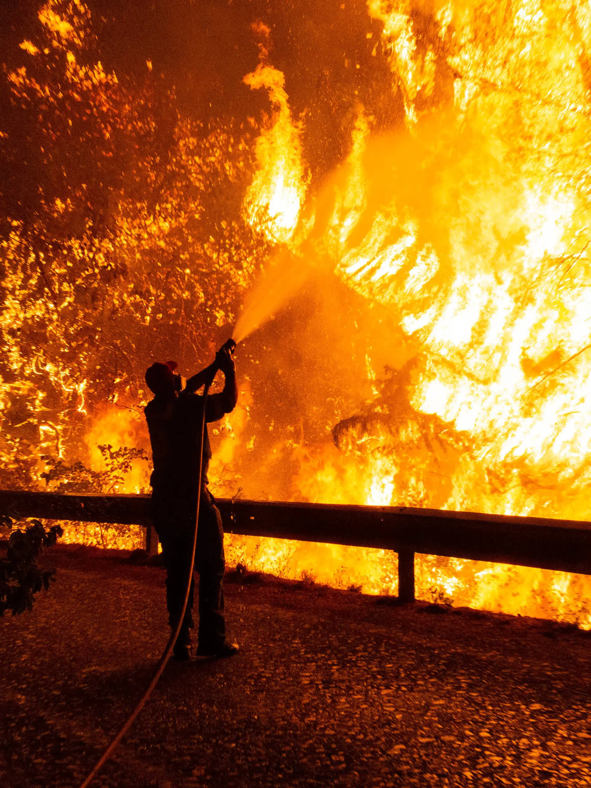 dpatopbilder - 05.08.2021, Griechenland, Athen: Freiwillige Helfer unterstützten einen Feuerwehrmann bei den Löscharbeiten eines Waldbrandes udn schlagen hinter ihm Flammen aus. Im von verheerenden Waldbränden getroffenen Griechenland spitzt sich die Lage weiter zu. Seit den frühen Morgenstunden fachten starke Westwinde am Freitag die zahlreichen Feuer weiter an. Foto: Marios Lolos/XinHua/dpa +++ dpa-Bildfunk +++
