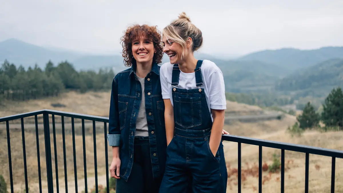 Two smiling woman standing on the cottage terrace and having fun together