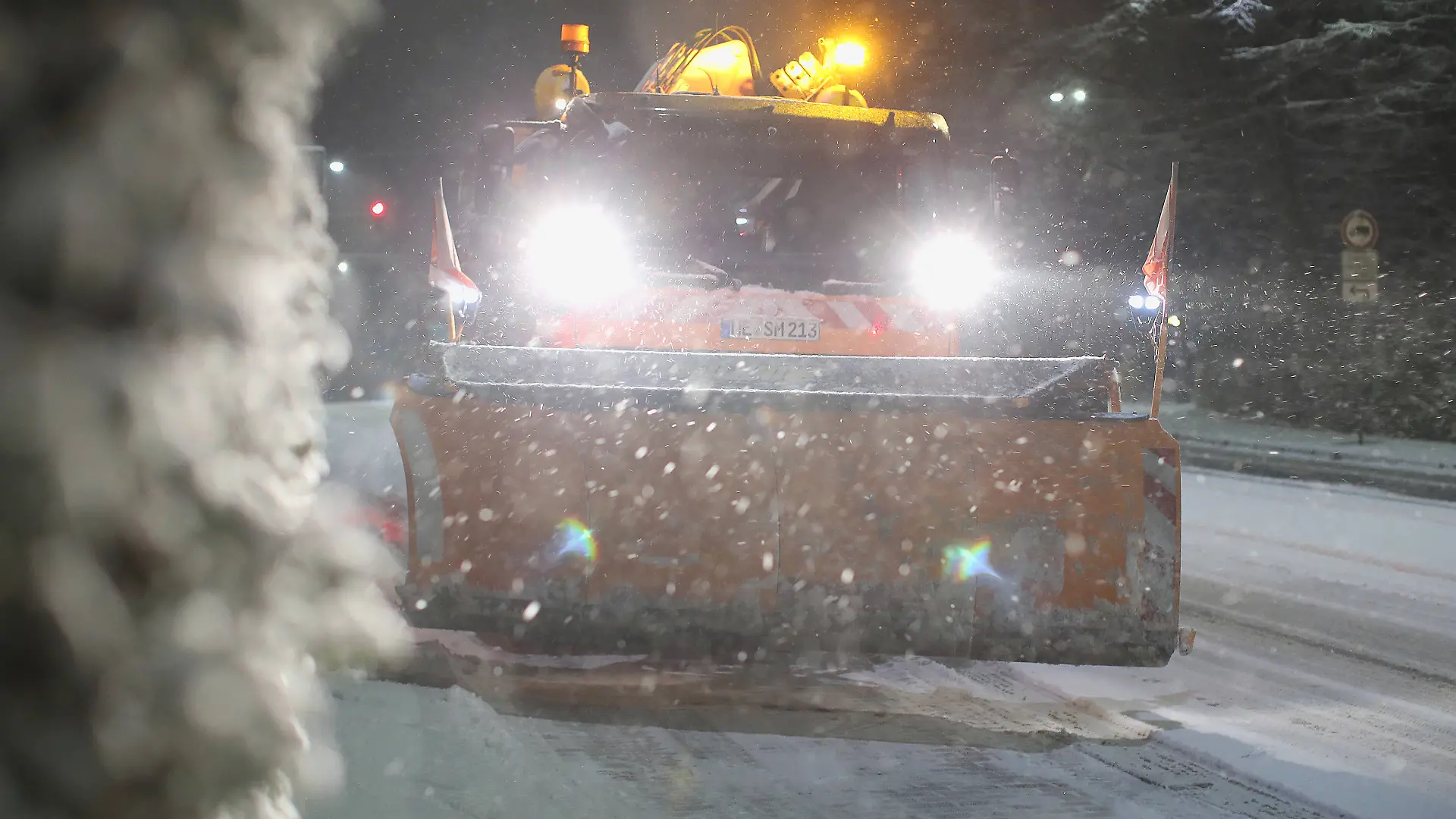 Ein Räumfahrzeug des Winterdienstes kämpft sich durch Schnee und glatte Straßen.