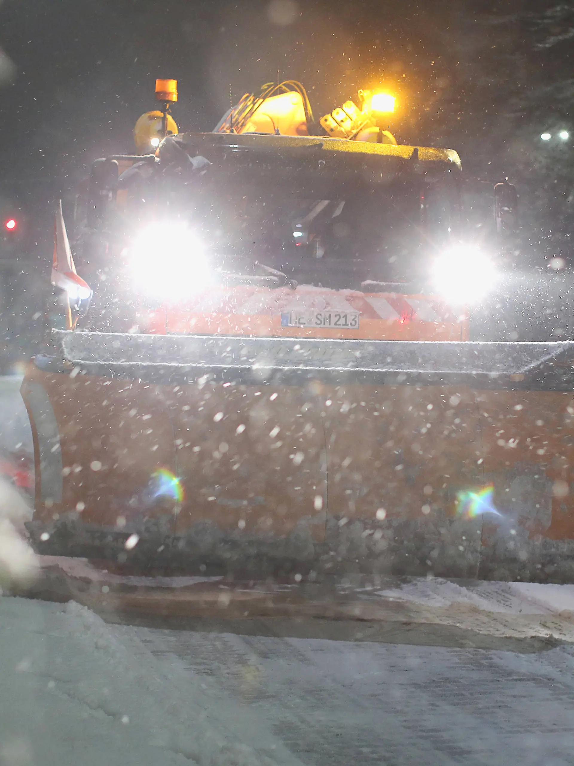Ein Räumfahrzeug des Winterdienstes kämpft sich durch Schnee und glatte Straßen.