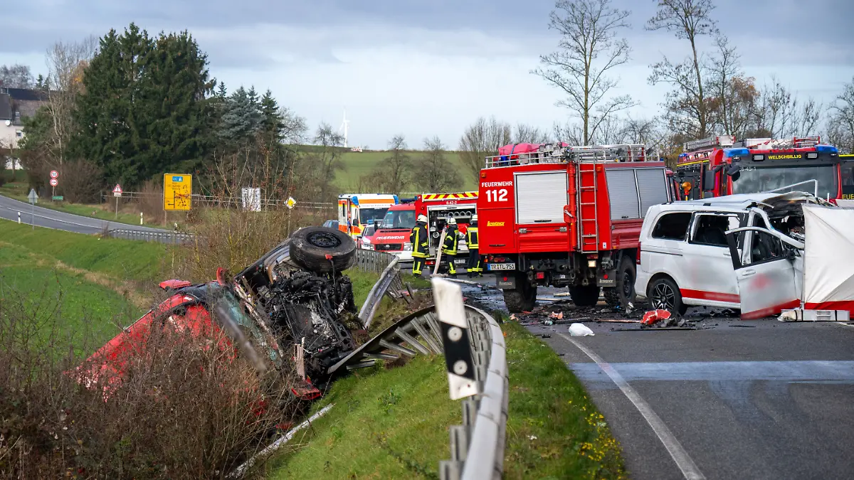 Ein Lastwagen liegt nach einem Frontalzusammenstoß mit einem Kleinbus (r) hinter der Leitplanke an einem Abhang an der Bundesstraße 51 bei Welschbillig.