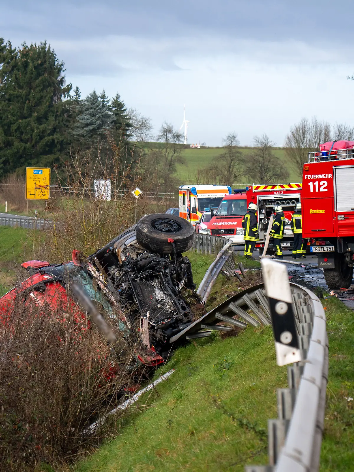 Ein Lastwagen liegt nach einem Frontalzusammenstoß mit einem Kleinbus (r) hinter der Leitplanke an einem Abhang an der Bundesstraße 51 bei Welschbillig.