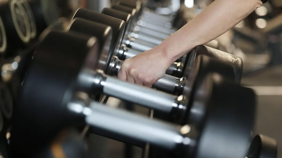 ARCHIV - 05.04.2022, Nordrhein-Westfalen, Köln: Ein Mensch greift Hanteln in einem Fitnessstudio. (zu dpa-Korr "Vatertag, Gym, Sale und Co: Ein ABC veränderter Bräuche und Begriffe") Foto: Oliver Berg/dpa +++ dpa-Bildfunk +++