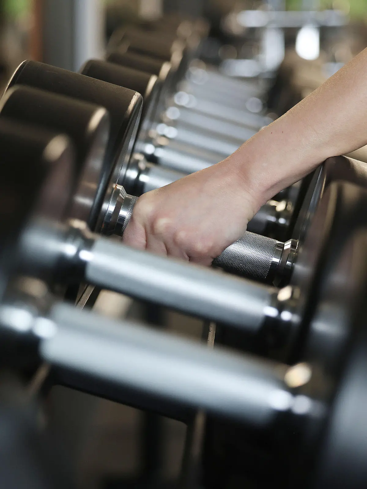 ARCHIV - 05.04.2022, Nordrhein-Westfalen, Köln: Ein Mensch greift Hanteln in einem Fitnessstudio. (zu dpa-Korr "Vatertag, Gym, Sale und Co: Ein ABC veränderter Bräuche und Begriffe") Foto: Oliver Berg/dpa +++ dpa-Bildfunk +++