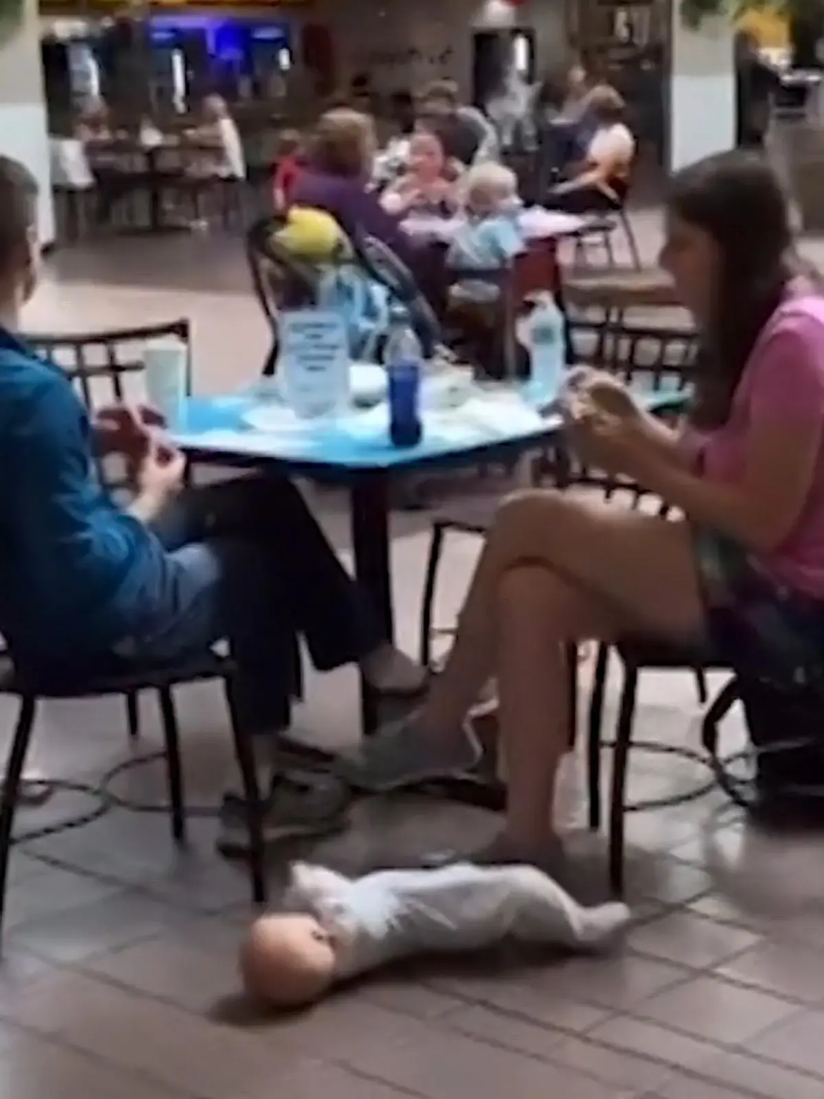 Elterliche Fürsorge sieht anders aus! Haben die mutmaßlichen Eltern ernsthaft in einem Einkaufszentrum am Tisch gesessen und gegessen, während ihr Baby neben ihnen auf dem kalten, dreckigen Fußboden liegt?