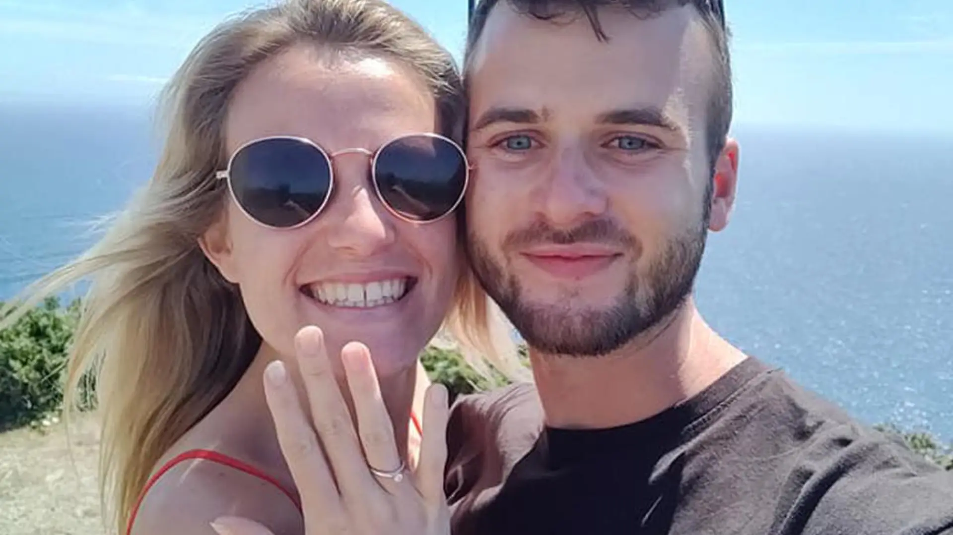 Der Englänger Ryan und seine Freundin Kate lachen in die Kamera. Sie hält ihre Hand mit ihrem Verlobungsring in die Kamera.