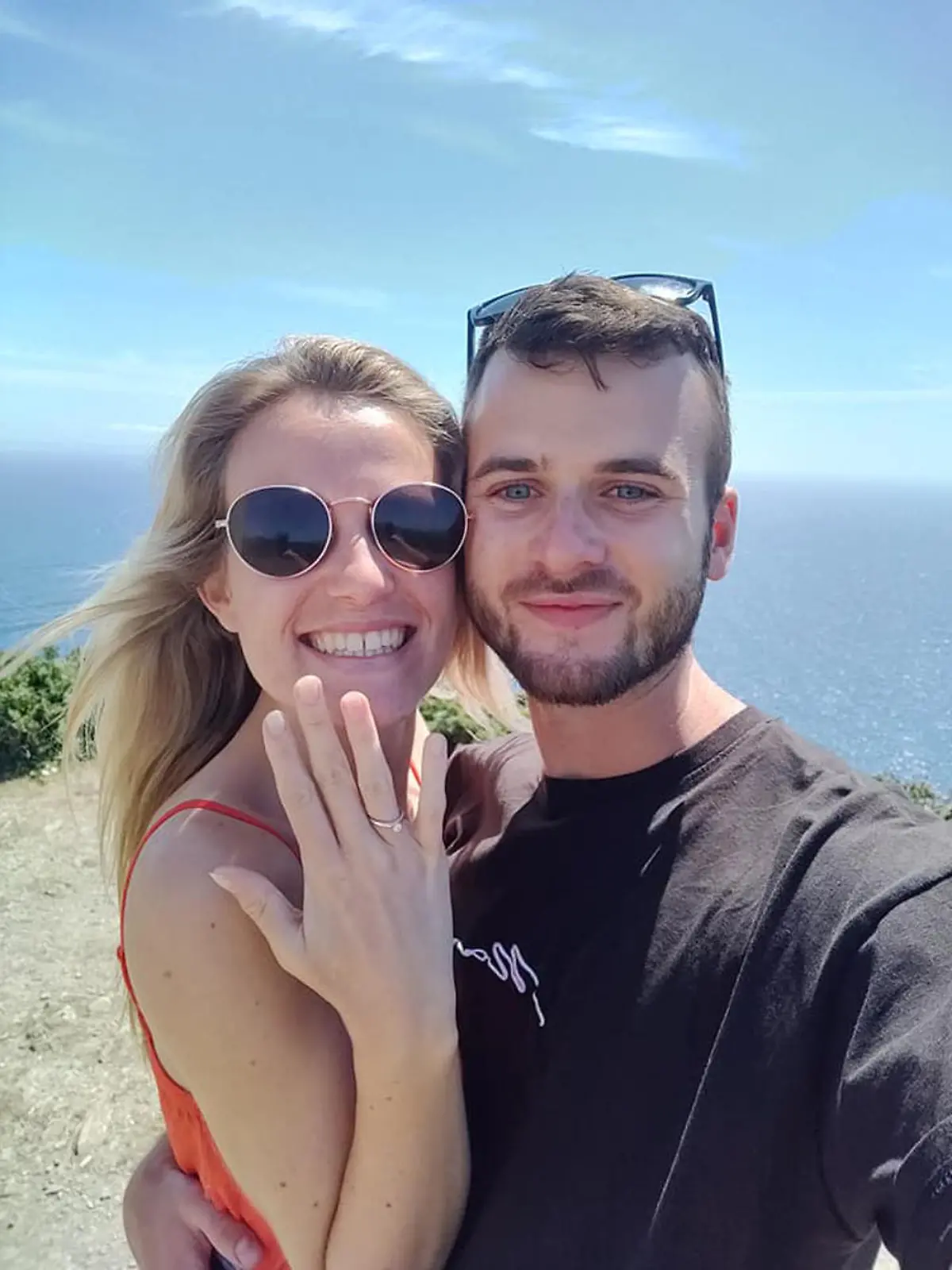 Der Englänger Ryan und seine Freundin Kate lachen in die Kamera. Sie hält ihre Hand mit ihrem Verlobungsring in die Kamera.