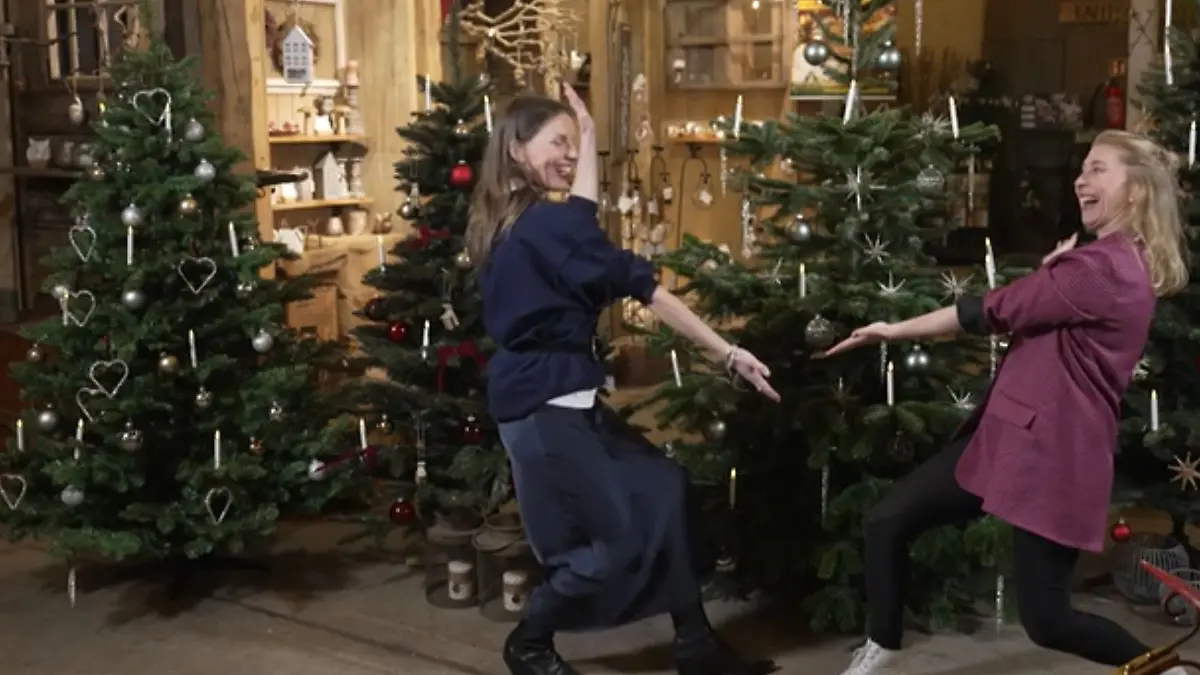 Reporterin und Expertin vor den künstlichen Weihnchtsbäumen