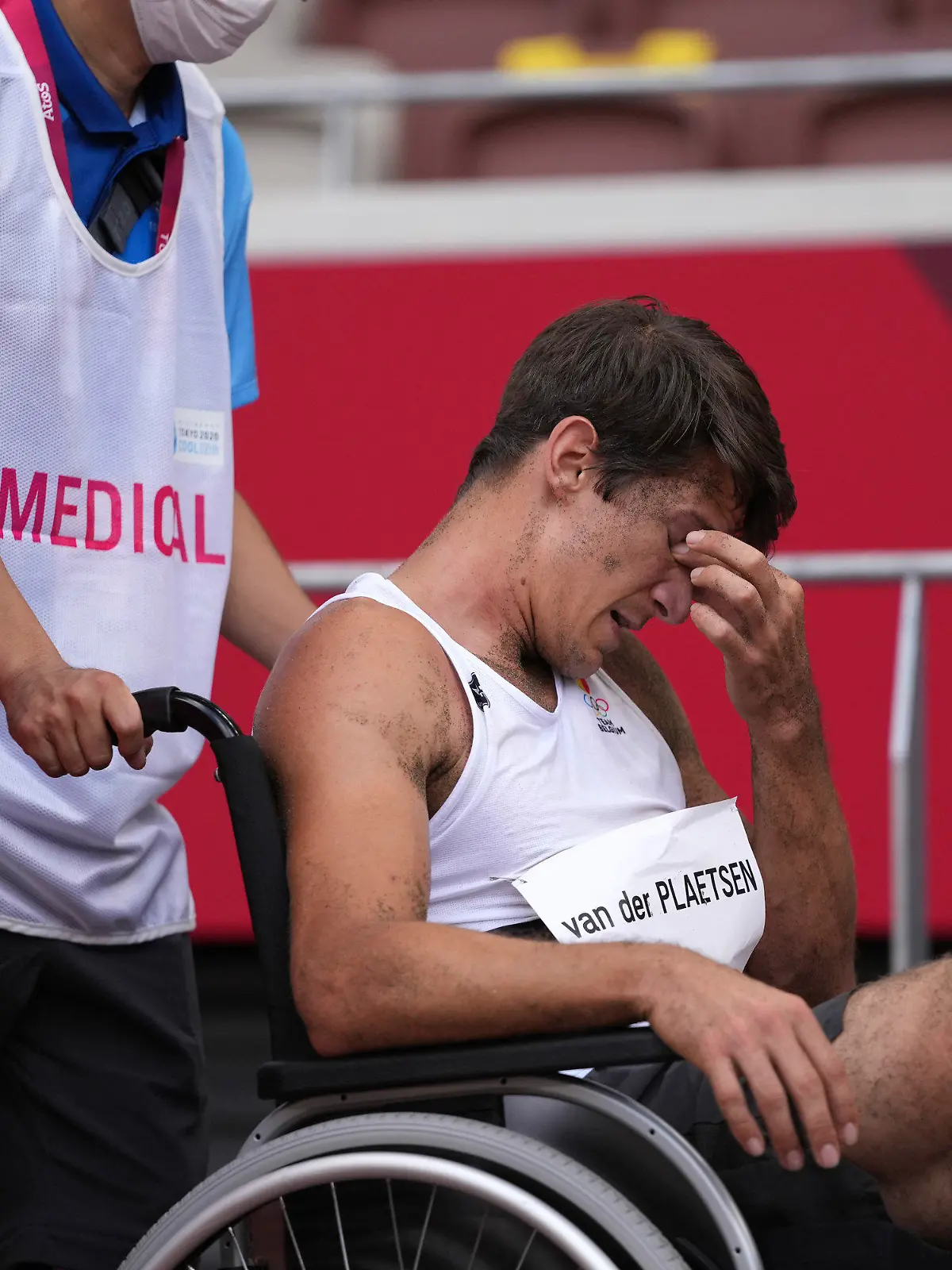 04.08.2021, Japan, Tokio: Leichtathletik: Olympia, Zehnkampf, Männer, Weitsprung im Olympiastadion. Thomas Van Der Plaetsen (M) aus Belgien sitzt nach einem Sturz in einem Rollstuhl und wird medizinisch betreut. Foto: Matthias Schrader/AP/dpa +++ dpa-Bildfunk +++