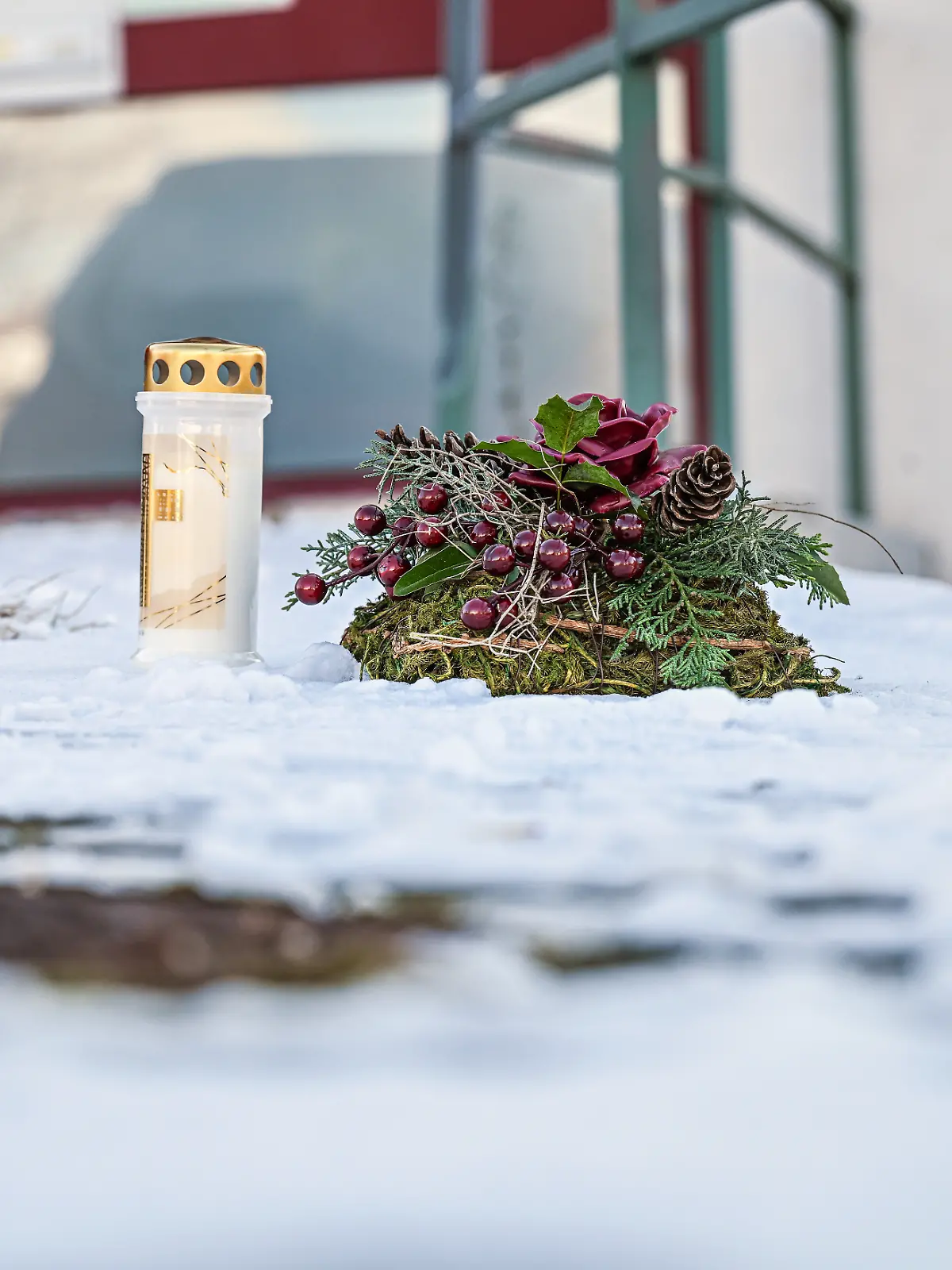 Eine Kerze steht neben einem Kranz an einem Tatort vor einem Firmengelände im Landkreis Reutlingen. 