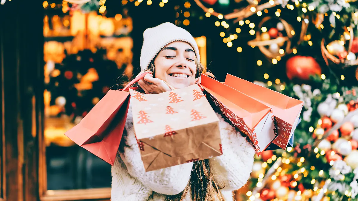 Frau mit Shoppingtüten in weihnachtlicher Einkaufsstraße.
